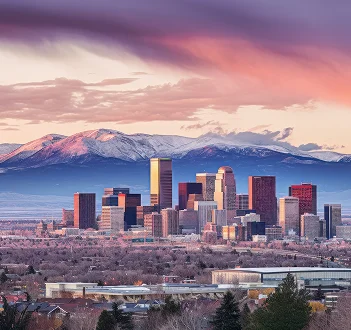 Aurora skyline with snow-covered mountains in the background under a pink and purple sunset sky.